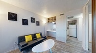 Located at 5310 S Hampton Rd in Dallas, TX, this efficiently designed one-bedroom, one-bathroom unit makes smart use of its compact footprint across a single floor. The living room serves as the welcoming heart of the space, featuring wood-look laminate flooring, a front-facing window that draws in natural light, and a textured ceiling. A built-in desk nook and open wall shelving seamlessly connect the living area to a secondary kitchen prep space, while a separate full kitchen offers cabinetry, a full-size refrigerator, dishwasher, microwave, and sink — providing notable functionality for the unit's size. A decorative wood slat partition adds a warm, modern design element that visually divides the living and sleeping areas. The bedroom is a calm, well-proportioned retreat with its own dedicated closet and textured ceiling. The full bathroom includes a tub-shower combination, a vanity with a light marble-style countertop, and wood-look flooring that ties in with the rest of the unit. A hallway connects the key spaces efficiently, contributing to a logical and practical layout throughout. The overall ambiance is clean, modern, and well-organized, making this unit a functional and comfortable living space.