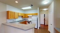 Located at 400 E Glade Rd in Grapevine, Texas, this single-floor unit offers a practical and comfortable layout designed with everyday living in mind. The entry opens into a living area finished with rich hardwood-style flooring that extends through the main living spaces, complemented by a ceiling fan overhead and an open sightline to the kitchen.

The kitchen is well-appointed with warm honey-toned oak cabinetry offering abundant upper and lower storage, granite-look countertops, a peninsula with a breakfast bar, and white appliances including a refrigerator, electric range, and dishwasher. A skylight panel above the kitchen adds brightness to the space.

The bedrooms are carpeted for comfort and feature ceiling fans and multiple windows that invite generous natural light and views of the surrounding landscape. The arched window detailing in one bedroom adds a classic architectural touch.

The bathroom is thoughtfully designed with accessibility in mind, featuring a walk-in shower equipped with safety grab bars and a fold-down bench, a wide vanity with dual sinks, wood cabinetry, and a large wall mirror with overhead lighting. The hardwood-style flooring continues throughout the bathroom for a cohesive finish. Overall, this unit provides a clean, functional, and accessible living environment.