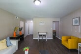 Located at 3006 Ember Dr in Decatur, GA, this single-floor residence offers a well-organized layout designed for comfortable everyday living. The open living area serves as the heart of the home, finished with rich dark hardwood-style flooring that runs throughout the main common spaces. A sliding glass door with vertical blinds allows natural light to filter in while providing outdoor access, and the neutral taupe walls create a warm, cohesive atmosphere throughout.

The kitchen is efficiently designed with white cabinetry, dark granite-look countertops, and a classic white subway tile backsplash. White appliances include a refrigerator, range, and dishwasher, and the hardwood-style flooring continues seamlessly into this space. A dedicated dining area sits just off the main living room, providing a practical spot for everyday meals.

Both bedrooms feature plush carpeting and neutral wall tones. The primary bedroom includes a walk-in closet with built-in hanging rods, offering generous storage. A second bedroom provides a window with outdoor views and ample room for furnishings.

The bathroom is a standout feature, showcasing floor-to-ceiling wood-look tile surround in the tub-shower combination, paired with light tile flooring and clean white fixtures, striking a balance between warmth and functionality.
