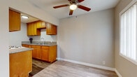 Located on Lakewood Boulevard in Downey, California, this single-floor, 2-bedroom, 1-bathroom unit offers a practical and well-appointed layout. Light wood-look flooring flows consistently throughout the space, creating a cohesive and easy-to-maintain aesthetic. The open living and dining area is bright and welcoming, with large windows fitted with vertical blinds that allow natural light to fill the room. A ceiling fan overhead adds comfort and airflow. The kitchen is efficiently designed with warm honey-toned wood cabinetry, granite countertops, a stainless steel sink, and a gas range, providing ample workspace and storage. Both bedrooms feature the same wood-look flooring and ceiling fans. The primary bedroom includes a mirrored sliding-door closet, maximizing the sense of space. The second bedroom is served by a dedicated closet as well. A single shared bathroom showcases floor-to-ceiling marble-style tile surrounding a full soaking tub and shower, complemented by a white vanity and wood-look flooring. The neutral warm-gray wall tones throughout the unit provide a clean, versatile backdrop. The space is efficiently organized across its compact footprint, making it a functional and move-in ready home in the Downey area.