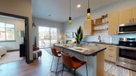 Located at 1538 Eighth Ave in Greeley, Colorado, this contemporary single-floor residence offers a well-designed open-concept layout that seamlessly connects the kitchen, dining, and living areas. The kitchen is appointed with light wood cabinetry, white subway tile backsplash, stainless steel appliances, open shelving, and a central island featuring a dark quartz countertop and bar seating — ideal for casual dining and entertaining. Warm wood-style flooring runs throughout the main living areas, complemented by soft neutral wall tones and recessed lighting with stylish pendant fixtures overhead. The living room is bright and inviting, benefiting from natural light and direct access to a private balcony that provides outdoor views of the surrounding neighborhood. The primary bedroom is a comfortable retreat, complete with a walk-in closet accessed through a sliding barn door. A second bedroom offers a large window with street views, adding to the airy feel of the space. The bathroom features a dual-sink vanity with matching wood cabinetry and dark quartz countertops, continuing the cohesive modern aesthetic found throughout. Overall, the residence presents a clean, contemporary design with thoughtful finishes and a functional, comfortable layout.