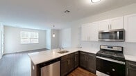 Located at 2140 Lakewood Rd in Toms River, NJ, this well-appointed one-bedroom, one-bathroom residence offers a thoughtfully designed single-floor layout with a clean, modern aesthetic throughout. The open-concept living, dining, and kitchen area serves as the heart of the home, featuring rich hardwood-style flooring, neutral walls, and abundant natural light from large windows and a glass-paneled exterior door that opens to a private outdoor area. The kitchen is well-equipped with stainless steel appliances — including a gas range, built-in microwave, and French door refrigerator — complemented by two-tone cabinetry in white and dark gray, white quartz countertops, a peninsula with a built-in sink, and a classic tile backsplash. The spacious bedroom offers plush wall-to-wall carpeting, a bright window with outdoor views, and access to a dedicated closet. The full bathroom includes a soaking tub with a shower surround, white cabinetry, and chrome fixtures. Throughout the residence, a consistent neutral color palette and clean finishes create a bright, move-in-ready atmosphere well-suited for comfortable everyday living.