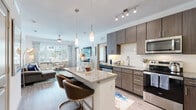 This well-appointed single-floor residence offers a thoughtfully designed open-concept layout that seamlessly connects the kitchen, dining, and living areas. The kitchen serves as a central focal point, featuring dark wood-tone cabinetry with sleek hardware, granite countertops, a white subway tile backsplash, and a full suite of stainless steel appliances including a refrigerator, range, microwave, and dishwasher. A kitchen island with a granite top and bar seating provides additional workspace and casual dining, illuminated by stylish pendant lighting overhead. Track lighting throughout the kitchen ensures ample task illumination.

The living area is bright and welcoming, with large windows allowing generous natural light and views of the surrounding outdoor environment. Ceiling fans are installed throughout, promoting comfortable airflow. Wood-look flooring extends across the main living areas, while plush carpeting adds warmth to the bedroom, which is generously sized with a closet and ceiling fan. The bathroom mirrors the home's design aesthetic, offering a granite-topped vanity with wood cabinetry and a large mirror. A versatile flex room provides additional functional living space.