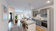 Located at 6000 Front St in Summerville, SC, this thoughtfully designed one-bedroom, one-bathroom residence offers a comfortable and modern living experience across a single floor. The open-concept kitchen and living area serves as the heart of the home, featuring a granite-topped island with bar seating, sleek gray cabinetry, white subway tile backsplash, and a full suite of stainless steel appliances including a refrigerator, range, microwave, and dishwasher. Pendant lighting over the island adds a polished touch. The living room is bright and inviting, with light wood-style flooring, a ceiling fan, and large glass doors that welcome natural light and provide access to the outdoors. The bedroom is a comfortable retreat with a ceiling fan, a window with natural light, and light wood-style flooring throughout. The bathroom includes a granite-topped vanity, wood-look tile flooring, and a tub-shower combination. A dedicated laundry room houses a full-size side-by-side washer and dryer with overhead wire shelving for added storage. A closet provides additional organization space, completing this efficiently designed and move-in-ready residence.