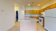 Located at 8197 Clark Road in Fort Meade, Maryland, this two-story home offers a well-organized layout across two levels. The kitchen is a central highlight, featuring warm honey-toned wood cabinetry that extends to the upper walls for ample storage, neutral countertops, and white appliances including a gas range, dishwasher, and refrigerator. A peninsula island adds additional prep and seating space, while light tile flooring ties the room together. Recessed lighting keeps the kitchen bright and practical.

The bedrooms are finished with plush wall-to-wall carpeting and receive generous natural light through multiple windows fitted with blinds. Ceiling fans provide added comfort, and closets with built-in shelving and hanging rods offer organized storage. The open floor plan visible from the dollhouse view reveals a spacious living area with hardwood-style flooring connecting the main living spaces.

The bathrooms are clean and functional, with one featuring a full tub-shower combination, and another offering a wide vanity with wood cabinetry and an extended countertop. Tile flooring throughout the bathrooms adds durability. Overall, the home presents a practical, comfortable layout suited for everyday living.