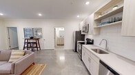 Located at 10865 Parkside Dr in Knoxville, TN, this well-designed one-bedroom, one-bathroom unit offers a clean, contemporary aesthetic throughout. The open-concept layout seamlessly connects the kitchen and living area, anchored by polished concrete floors that run throughout the main space and give it a sleek, modern character.

The kitchen is equipped with stainless steel appliances — including a refrigerator, range, microwave, and dishwasher — complemented by light wood cabinetry, open shelving, a subway tile backsplash, and light quartz countertops. Recessed lighting illuminates the space efficiently.

The living area is generously proportioned, featuring crown molding, recessed lighting, and a set of glass French doors that open to a private balcony with views of surrounding greenery, allowing ample natural light to fill the room.

The bedroom is a comfortable retreat, carpeted for warmth, and fitted with a ceiling fan, a large window overlooking the outdoors, and access to a dedicated closet. The bathroom is finished with light wood vanity cabinetry, tile flooring, and a glass-enclosed walk-in shower. The overall palette of soft whites and neutrals creates a bright, cohesive ambiance throughout the unit.