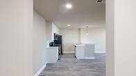 This single-floor residence offers a thoughtfully designed layout encompassing two bedrooms, two bathrooms, and a combined kitchen and living area. The open-concept kitchen and living space serves as the heart of the home, featuring light grey wood-look plank flooring that flows seamlessly throughout. The kitchen is outfitted with tall white shaker-style cabinetry, light-toned quartz countertops, stainless steel appliances including a refrigerator, range, microwave, and dishwasher, and a central island with a built-in sink and pendant lighting above. The expansive living area provides generous room for various furniture arrangements.

Both bedrooms offer comfortable proportions, neutral warm-toned walls, and dedicated closets with built-in shelving. The primary bedroom is particularly spacious, providing ample room for large furnishings. The two bathrooms are finished with tile flooring, white vanities with quartz countertops, and tile-surround soaking tubs. Hallways connect each area efficiently, contributing to a logical and functional flow. The overall aesthetic is clean and modern, with a neutral color palette, recessed lighting, and consistent flooring creating a cohesive and move-in-ready environment throughout.
