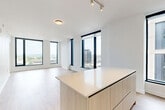 Located at 1320 4th St NE in Washington, DC's vibrant NoMa neighborhood, this modern 2-bedroom, 2-bathroom residence offers a thoughtfully designed single-level layout. Light wood-tone flooring runs throughout, complementing the clean white walls and contemporary finishes that define the space.

The open-concept living and dining area is bathed in natural light through expansive floor-to-ceiling windows with sleek black frames, offering impressive city views of the Washington skyline. The kitchen is a standout feature, equipped with stainless steel appliances, light wood cabinetry extending to the ceiling, a white glass backsplash, and a generous center island with a waterfall countertop — ideal for both cooking and entertaining.

The two bedrooms are well-proportioned, with the primary bedroom offering direct access to its own bathroom. Both bathrooms are stylishly finished, featuring hexagonal floor tile, white subway tile surrounding the soaking tub and shower, matte black fixtures, and light wood floating vanities. Additional highlights include a den, a dedicated utility room, three closets, and a hallway connecting the private quarters. The result is a polished, modern residence with a clean, urban aesthetic.