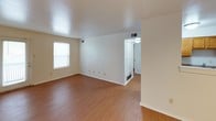 This single-floor unit offers a clean, functional layout with a bright and open feel throughout. The living area is spacious and airy, featuring warm hardwood-style flooring that extends seamlessly across the main living spaces and bedroom. White walls and neutral tones create a light, welcoming ambiance, while windows fitted with horizontal blinds allow for natural light and privacy control. A ceiling fan with a built-in light fixture is installed in the bedroom, adding both comfort and practicality to the space.

The kitchen is efficiently designed, equipped with honey-toned oak cabinetry offering ample storage above and below the counter. A double-basin stainless steel sink, laminate countertops, a black refrigerator, and a black dishwasher complete the functional setup. A louvered closet door adjacent to the kitchen provides additional storage access.

The bathroom is straightforward and well-maintained, featuring a full-size soaking tub with a tub/shower combination, marble-style wall surround, a chrome shower curtain rod, and a grab bar for added accessibility. The toilet and surrounding surfaces are finished in crisp white, contributing to the clean overall aesthetic. The unit's single-floor design ensures easy accessibility and a cohesive flow throughout the space.
