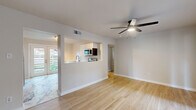 This single-story 2-bedroom, 1-bathroom home offers a thoughtfully designed layout with modern updates throughout. The open-concept living and dining area is highlighted by light hardwood flooring, a ceiling fan with integrated lighting, and a pass-through window that connects seamlessly to the kitchen — filling the space with an airy, connected feel. French doors in the living area provide direct access to the outdoors and allow natural light to pour in.

The kitchen is a standout feature, boasting white shaker cabinetry, sleek quartz countertops, a matte gold faucet, and a full suite of stainless steel appliances including a dishwasher, range, and built-in microwave. Striking marble-look tile flooring adds an elegant touch to this functional space.

Both bedrooms are comfortably sized, with the generously proportioned primary bedroom offering mirrored sliding closet doors and a ceiling fan. The second bedroom also features a ceiling fan and a window with natural light. Each room continues the light hardwood flooring found throughout the home.

The bathroom is finished with floor-to-ceiling marble-look tile, a soaking tub, and matte black fixtures, lending a clean, contemporary aesthetic. Outside, a private fenced backyard features a fire pit, mature trees, and green lawn space — ideal for outdoor relaxation and entertaining.