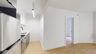 Located at 1811 Tamarind Ave in the heart of Hollywood, Los Angeles, this single-floor unit offers a clean, modern aesthetic defined by crisp white walls and warm light wood flooring that runs throughout. The open living area is bright and airy, benefiting from a large window with vertical blinds that invites natural light and includes a wall-mounted AC unit for year-round comfort. The contemporary kitchen is thoughtfully appointed with stainless steel appliances — including a gas range, refrigerator, and over-the-range microwave — complemented by gray lower cabinetry, white upper cabinets, quartz countertops, a deep undermount stainless steel sink with a matte black faucet, and a striking white hexagonal tile backsplash. A pendant light fixture adds an industrial touch overhead. The bedroom features mirrored sliding closet doors that enhance the sense of space, while the bathroom is finished with classic white subway tile walls and large-format floor tile, maintaining the unit's clean, cohesive palette. Matte black hardware accents appear consistently throughout, lending a modern, unified feel. The thoughtful layout and quality finishes make this a well-designed, move-in-ready space in a prime Los Angeles location.