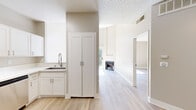This thoughtfully laid-out 2-bedroom, 1-bathroom single-floor home combines modern finishes with functional design throughout. Light-toned hardwood-style flooring runs continuously across the space, complementing the warm neutral palette on the walls and creating a cohesive, airy atmosphere.

The kitchen is well-appointed with crisp white shaker cabinetry, clean white countertops, and a full suite of stainless steel appliances including a gas range, over-the-range microwave, dishwasher, and refrigerator. A dedicated pantry cabinet and under-sink storage provide ample organization. The kitchen opens conveniently toward the living area and hallway.

The living room is a standout, featuring soaring vaulted ceilings, a circular clerestory window that draws in natural light, a corner fireplace, and sliding glass doors that open to an outdoor balcony with greenery views — lending the space an open, airy character.

Both bedrooms are well-proportioned and filled with natural light. The primary bedroom includes sliding glass doors to the balcony, while the second bedroom features a large window with outdoor views. A dedicated closet with built-in shelving provides convenient storage.

The bathroom is clean and functional, offering a tub-shower combination, a white vanity with a single sink, and a well-lit mirror above. A hallway connects the bedrooms, bathroom, and closet seamlessly.