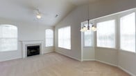 This single-story home offers a thoughtfully designed layout with a warm, neutral color palette and carpeted flooring throughout. The main living area is a standout feature, boasting soaring vaulted ceilings that lend a sense of spaciousness and grandeur. Multiple large windows flood the room with natural light, creating a bright and airy atmosphere. A ceiling fan provides year-round comfort, while a tiled fireplace serves as a classic focal point, adding both style and function to the space. A chandelier elegantly defines the dining area, which also benefits from ample window coverage and outdoor views.

Transitioning through the home, a well-appointed hallway leads to additional rooms, each finished with the same clean, neutral tones and carpet underfoot. Crown molding adds a refined architectural detail throughout. A particularly practical feature is a built-in shelving and desk nook — ideal for use as a study station or display area — recessed neatly into the wall. This thoughtful built-in detail maximizes utility without sacrificing floor space. Overall, the home presents a clean, move-in-ready environment with a balance of classic design elements and functional living spaces.