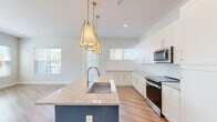 Located at 2648 Sandy Plains Rd in Marietta, GA, this thoughtfully designed 2-bedroom, 1-bathroom residence offers a generous single-floor layout filled with contemporary finishes and functional living spaces. Light-toned hardwood flooring flows through the main living areas, while a bright, wide hallway leads seamlessly into the open-concept kitchen and living room. The kitchen is a standout feature, showcasing a bold teal island topped with granite countertops, white shaker-style cabinetry with gold hardware, subway tile backsplash, stainless steel appliances, and elegant pendant lighting. Multiple windows bathe the space in natural light and offer views of the surrounding greenery. The primary bedroom is generously proportioned, carpeted for comfort, and includes direct access to a walk-in closet with built-in wire shelving systems. The second bedroom is equally well-lit with a ceiling fan and its own closet. The bathroom features large-format marble-look tile flooring, a granite vanity with gold hardware, a lighted mirror, and built-in open shelving. Additional spaces include a den, laundry room, utility room, and a private balcony with wrought iron railings overlooking the landscaped surroundings.