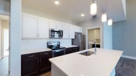 Located at 6770 Printers Blvd in New Albany, Ohio, this well-appointed two-story residence offers a thoughtfully designed layout across two levels. The kitchen serves as a standout centerpiece, showcasing a two-tone cabinet design with crisp white upper cabinetry and rich dark lower cabinets, complemented by a classic white subway tile backsplash. A large kitchen island with a sleek quartz countertop and an undermount sink provides generous prep and gathering space, while pendant lighting adds a refined finishing touch. Stainless steel appliances, including a French door refrigerator, electric range, and built-in microwave, complete the modern culinary setup. Recessed lighting throughout the kitchen ensures a bright, welcoming atmosphere. A dedicated laundry area is conveniently accessible just off the kitchen, adding to the home's practical layout. The overall design aesthetic is clean and contemporary, balancing neutral tones with bold contrasts for a timeless look. Spread across two floors, the home offers ample living space, making it well-suited for a variety of lifestyles. Situated in the vibrant New Albany community, this property combines modern finishes with functional design in a desirable central Ohio location.