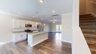 Located in Chattanooga, TN, this two-story home offers four bedrooms and three bathrooms thoughtfully distributed across two well-proportioned floors. The main level centers around an open-concept kitchen and living area, creating a seamless flow for everyday living and entertaining. The kitchen is appointed with white shaker cabinetry, a subway tile backsplash, granite countertops, stainless steel appliances, and a central island with a built-in sink — all illuminated by stylish pendant lighting and recessed fixtures. Rich hardwood flooring extends throughout the main level, complementing the crown molding and neutral warm-toned walls. The living room is highlighted by a ceiling fan and a set of glass French doors that invite natural light and provide outdoor views. A staircase connects to the upper floor, where the bedrooms are finished with plush carpet and large windows that bring in ample natural light. The generously sized primary bedroom offers a comfortable retreat. Three full bathrooms include tub-shower combinations with clean, bright finishes. A utility room and multiple closets add practical storage, while two hallways ensure smooth circulation throughout the home.