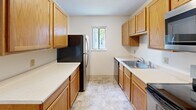 This two-story home offers a functional and well-organized layout spread across two floors. The main level houses the open kitchen and living room area, finished with light wood-tone laminate flooring and a ceiling fan that enhances airflow and comfort. The kitchen is efficiently designed in a galley style, featuring warm oak cabinetry, white countertops, tile flooring, and stainless steel appliances including a refrigerator, dishwasher, and range. A window above the sink brings in natural light, keeping the space bright and practical.

Upstairs, both bedrooms are carpeted and finished in neutral tones, creating a calm and restful atmosphere. The primary bedroom offers generous proportions with dual sliding-door closets providing ample storage. The second bedroom includes a window with views of surrounding greenery. A hallway connects the upper level, which also includes the shared full bathroom, finished with tile flooring, oak vanity cabinetry, and a shower-tub combination.

The exterior features a privacy fence with decorative lattice topping, enclosing a grassy yard area surrounded by mature trees — offering a peaceful and private outdoor retreat.