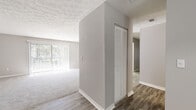 This single-story residence on Maple in Jacksonville, Florida offers a well-organized layout with a consistent, neutral design aesthetic throughout. The entry area transitions between wood-look flooring and plush carpeting, with a built-in closet featuring louvered doors providing convenient storage. The living area is bright and open, benefiting from natural light streaming through vertical blinds that overlook outdoor greenery.

The kitchen is thoughtfully updated, showcasing white shaker-style cabinetry, marble-look countertops, a mosaic tile backsplash, and a full suite of stainless steel appliances including a range, dishwasher, and refrigerator. Light wood-look tile flooring and a window above the sink add to the clean, functional feel of the space.

The bedrooms are carpeted and finished in warm gray tones, each receiving natural light through blinds-fitted windows. One bedroom features a sliding glass door that welcomes abundant light from outside. The bathroom is finished with wood-look flooring, a marble-look vanity countertop, white cabinetry, and a louvered-door medicine cabinet, creating a clean and cohesive aesthetic. Textured ceilings are present throughout the unit.