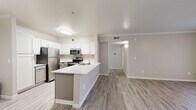 This well-appointed 4-bedroom, 2-bathroom single-story home offers a thoughtfully designed layout that maximizes both functionality and comfort. The open-concept living area seamlessly connects the kitchen, dining, and living spaces, creating an inviting atmosphere for everyday living and entertaining. The kitchen is a standout feature, showcasing white cabinetry, a white quartz peninsula with an undermount sink, and a full suite of stainless steel appliances including a refrigerator, range, and microwave. Light wood-style luxury vinyl flooring runs throughout the common areas, complemented by clean white baseboards and crown molding details that lend a polished finish. The dining area is highlighted by a pendant light fixture and flows naturally into the living space. The four bedrooms offer a mix of flooring options, with the primary and select bedrooms featuring plush carpeting, while neutral, light-toned walls create a bright and airy feel. Windows in the bedrooms allow for natural light and exterior views. The two bathrooms are finished with gray cabinetry, light countertops, and tub-shower combinations with tile surrounds. Two closets provide additional storage. The overall design palette of soft neutrals, modern fixtures, and cohesive finishes gives this home a clean, move-in-ready appeal.