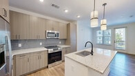 Located at 3238 Hidden Forest Ct in Marietta, GA, this thoughtfully designed one-bedroom, one-bathroom residence offers a clean, contemporary aesthetic throughout its efficiently laid-out single floor. The open-concept kitchen and dining area serves as the heart of the home, showcasing light wood cabinetry, granite countertops, a subway tile backsplash, and a full suite of stainless steel appliances including a French door refrigerator, electric range with microwave, and dishwasher. A central kitchen island with an undermount sink and matte black faucet provides additional prep space and casual dining functionality, illuminated by stylish pendant lighting overhead. Warm hardwood-style flooring runs throughout the main living areas, complementing the bright, neutral color palette. The dining and living area features access to an outdoor space through a glass door, filling the room with natural light. The bedroom offers plush carpeting, a ceiling fan, and a well-sized window with outdoor views. The full bathroom is well-appointed with a granite vanity, matte black fixtures, a framed mirror, a glass-enclosed shower, and direct access to a dedicated walk-in closet. A separate laundry area adds everyday convenience to this polished, move-in-ready residence.