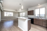 Located at 1050 Murphy St in Des Moines, Iowa, this single-floor, two-bedroom, two-bathroom residence offers a thoughtfully designed layout with a comfortable sense of space. The open-concept kitchen and living area serves as the heart of the unit, featuring light wood-look flooring, multiple windows that invite natural light, and a ceiling fan overhead. The kitchen is well-equipped with rich, medium-toned wood cabinetry, granite-patterned countertops, black appliances including a range, microwave, and dishwasher, and a peninsula that provides additional counter space and separates the kitchen from the living area. Pendant lighting accents the peninsula, adding a contemporary touch.

The bedrooms are carpeted for comfort, each with a ceiling fan and windows offering outdoor views. The primary bedroom includes access to a walk-in closet with wire shelving, and a second walk-in closet provides additional storage elsewhere in the unit. Both bathrooms feature wood-tone vanities with granite-style countertops and tub-shower combinations. A dedicated in-unit laundry room houses a full-sized washer and dryer with overhead wire shelving. The overall palette is neutral and clean throughout.