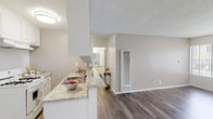 This single-story space offers a practical and well-appointed layout designed for comfortable everyday living. The open-concept living and kitchen area serves as the heart of the unit, where wood-look vinyl plank flooring extends throughout, complemented by neutral gray-toned walls and a textured ceiling. A ceiling fan is positioned in the living area, which also features a wall-mounted HVAC unit and vertical blinds allowing natural light to filter in.

The kitchen is defined by a peninsula-style breakfast bar with granite-look countertops, white cabinetry, an undermount sink, and a white gas range with overhead cabinetry and ventilation. The layout allows for easy flow between the kitchen and living spaces.

The bathroom features a clean, all-white tub and shower combination with chrome fixtures, alongside a separate vanity area outfitted with white cabinetry, granite-look countertops, a single undermount sink, and a wide mirror above.

The bedroom offers plush wall-to-wall carpeting, a window with vertical blinds providing natural light, and a sliding-door closet with a built-in rod and shelving. The overall aesthetic throughout is neutral, clean, and move-in ready.