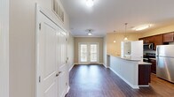 Located along Providence Main Street NW in Huntsville, Alabama, this one-bedroom, one-bathroom residence offers a thoughtfully designed layout across a single floor. Rich, dark hardwood-style flooring runs throughout the main living areas, creating a warm and cohesive aesthetic. The open living room is bathed in natural light, courtesy of French doors that invite the outdoors in, and is complemented by crown molding and a ceiling fan overhead.

The kitchen is a functional highlight, featuring rich dark cabinetry, granite countertops, stainless steel appliances — including a refrigerator, range, and microwave — and a breakfast bar with pendant lighting that flows seamlessly into the living space. A dedicated laundry room with shelving and a window providing natural light adds everyday convenience.

The generously sized bedroom is carpeted for comfort, with a ceiling fan, ample natural light from large windows, and direct access to the bathroom. The bathroom is well-appointed with dark wood vanity cabinetry, stone-topped counters, a large mirror, and a tub-shower combination set over light tile flooring. Throughout the residence, neutral tones and clean finishes create a bright, inviting ambiance ideal for comfortable everyday living.