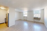 Located at 2215 Arch Street in Philadelphia's vibrant Logan Square neighborhood, this efficiently designed unit offers a clean, modern aesthetic throughout its single-floor layout. Light-toned laminate flooring runs continuously through the space, complementing the crisp white walls and creating a bright, cohesive feel.

The open combined kitchen and living area forms the heart of the unit. The living area is well-lit by two windows that invite natural light and offer city views, with a wall-mounted HVAC unit providing climate control. The space is open and versatile, offering ample room for both living and dining arrangements.

The galley-style kitchen is thoughtfully appointed with white shaker cabinetry, granite countertops, a subway tile backsplash, a stainless steel sink, and stainless steel appliances including a refrigerator, range, and dishwasher — delivering both style and functionality in a compact footprint.

A central hallway connects the living area to the bathroom and three closets, providing generous storage throughout. The hallway features a mirrored sliding closet door, enhancing the sense of space. The bathroom is finished with classic white subway tile in the tub surround, a soaking bathtub, a vanity, and neutral stone-look tile flooring, achieving a clean and timeless look.
