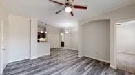 Located in Baytown, TX, this well-appointed one-bedroom, one-bathroom residence offers a thoughtfully designed single-floor layout. The combined kitchen and living area forms the heart of the home, featuring stylish gray wood-look vinyl flooring that flows throughout the main spaces. The kitchen is equipped with rich dark-wood cabinetry, granite-style countertops, a peninsula with pendant lighting, and black appliances including a refrigerator, range, microwave, and dishwasher. Crown molding adds a refined touch throughout. The living area is bright and open, highlighted by a ceiling fan, an elegant arched entryway, and a sliding glass door that opens to a private patio with pleasant outdoor views. The bedroom is a comfortable retreat with plush carpeting, crown molding, a ceiling fan, and a window that allows natural light. It is complemented by a spacious walk-in closet fitted with wire shelving and hanging rods for ample storage. The bathroom features a tub-shower combo with tiled surround, a dark-wood vanity with granite-style countertop, and wood-look flooring that ties the space together cohesively. Neutral tones and clean finishes throughout create a fresh and move-in ready atmosphere.