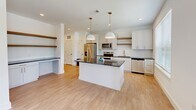 Located at 7900 Kaplan Road in Covington, Georgia, this thoughtfully designed one-bedroom, one-bathroom residence offers a functional and modern single-floor layout. The open-concept kitchen serves as the centerpiece of the home, showcasing white shaker cabinetry, a classic subway tile backsplash, dark granite countertops, and a central island illuminated by two pendant lights with brushed gold accents. Stainless steel appliances — including a refrigerator, range, microwave, and dishwasher — complete the kitchen's contemporary appeal. Light hardwood-style flooring runs throughout the main living areas, complemented by open shelving and a dedicated workspace nook. Natural light flows in through large windows fitted with horizontal blinds. The bedroom offers soft carpeting underfoot, a ceiling fan, a window with outdoor views of the surrounding community, and direct access to a well-organized walk-in closet with built-in shelving. The bathroom continues the home's clean aesthetic with granite-topped vanity cabinetry featuring gold hardware, a full tub-shower combo with white subway tile surround, brushed gold fixtures, and matching hardwood-style flooring. The overall design balances modern finishes with practical, comfortable living.