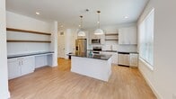 Located at 7900 Kaplan Road in Covington, Georgia, this thoughtfully designed one-bedroom, one-bathroom residence offers a functional and modern single-floor layout. The open-concept kitchen serves as the centerpiece of the home, showcasing white shaker cabinetry, a classic subway tile backsplash, dark granite countertops, and a central island illuminated by two pendant lights with brushed gold accents. Stainless steel appliances — including a refrigerator, range, microwave, and dishwasher — complete the kitchen's contemporary appeal. Light hardwood-style flooring runs throughout the main living areas, complemented by open shelving and a dedicated workspace nook. Natural light flows in through large windows fitted with horizontal blinds. The bedroom offers soft carpeting underfoot, a ceiling fan, a window with outdoor views of the surrounding community, and direct access to a well-organized walk-in closet with built-in shelving. The bathroom continues the home's clean aesthetic with granite-topped vanity cabinetry featuring gold hardware, a full tub-shower combo with white subway tile surround, brushed gold fixtures, and matching hardwood-style flooring. The overall design balances modern finishes with practical, comfortable living.