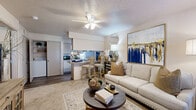 Located in Benton, Arkansas, this efficiently designed one-bedroom, one-bathroom residence offers a thoughtful single-floor layout that maximizes every square foot. The open-concept living room and kitchen serve as the heart of the home, where a ceiling fan overhead complements the warm, carpeted living area. Natural light filters in through a large window, brightening the space alongside a bold, blue-and-gold canvas that adds a striking decorative focal point. The kitchen features wood-toned cabinetry, a peninsular breakfast bar with bar seating, hardwood-style flooring, and white appliances including a dishwasher, refrigerator, and range — offering a functional and stylish cooking space. A hallway leads to the private bedroom, which is generously sized and outfitted with plush carpet, natural light from a double window, a ceiling fan, and textured ceiling detail. The full bathroom is accessed via a corridor and includes a vanity with light wood cabinetry, a mirror, and hardwood-style flooring. A laundry area with washer and dryer hookups is also accessible within the unit, adding day-to-day convenience. The overall ambiance is warm, practical, and well-suited for comfortable single-occupancy living.