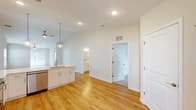 This single-floor residence offers a clean, modern design with an open-concept layout that promotes a seamless flow between living spaces. The main living and dining area features vaulted ceilings with ceiling fans, warm hardwood-style flooring, and multiple windows that invite an abundance of natural light, creating a bright and airy atmosphere throughout.

The kitchen is well-equipped with crisp white shaker-style cabinetry extending to the ceiling, light quartz countertops, a classic white subway tile backsplash, and a full suite of stainless steel appliances including a refrigerator, electric range, over-the-range microwave, and dishwasher. A kitchen island with an undermount sink and pendant lighting adds both functionality and style.

The primary bathroom offers a double-sink vanity with brushed nickel fixtures, a large mirror with elegant vanity lighting, a walk-in glass-door shower, and hardwood-style flooring. A second full bathroom includes a tub/shower combination and matching white cabinetry. The spacious walk-in closet features built-in wire shelving for organized storage. Bedroom spaces are carpeted for comfort, providing a soft contrast to the hardwood-style floors found throughout the main areas. Recessed lighting throughout completes this well-designed home.