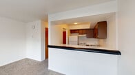 Located at 4500 Wilmington Ave in Kettering, Ohio, this one-bedroom, two-bathroom unit offers a practical and functional single-floor layout. The entryway opens through a hallway that connects the main living areas, providing a logical flow throughout the space. The kitchen features warm wood-toned cabinetry, white countertops, a stainless steel sink, a dishwasher, and a white refrigerator and range. A pass-through counter connects the kitchen to the living area, enhancing the open feel between the two spaces. The carpeted living area receives natural light through a sliding glass door and windows. The generously sized primary bedroom is carpeted and includes a window overlooking surrounding greenery, with baseboard heating and access to a dedicated bathroom vanity area featuring a large mirror, white cabinetry, and recessed lighting. A second full bathroom includes tile flooring, baseboard heating, and a towel bar. Throughout the unit, white walls and neutral carpet tones create a clean, consistent aesthetic. The layout is efficient and well-organized, with a hallway providing access to all rooms, including a closet with warm wood-toned doors.