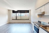 Located at 55 Bradford Street in Providence, Rhode Island, this efficiently designed single-floor unit offers a thoughtful open-concept layout that combines the living, dining, and kitchen areas into one cohesive space. Durable wood-look plank flooring runs throughout the main area, complemented by neutral-toned walls and recessed lighting that keep the interior feeling bright and clean. A wide bank of windows fitted with dual-shade roller blinds lines one wall, drawing in natural light while providing street views and privacy control.

The kitchen is well-appointed with white shaker-style cabinetry, dark granite countertops, and a full suite of stainless steel appliances including a gas range, dishwasher, and refrigerator — all arranged along a single efficient run. The open design allows the kitchen to flow seamlessly into the living and dining areas, maximizing the usability of the space.

The bathroom features marble-look tile flooring, built-in open shelving, and a glass-door walk-in shower, offering a clean and functional design. A dedicated closet and in-unit laundry area add everyday practicality. Overall, the unit presents a modern, move-in-ready aesthetic suited for urban living in the heart of Providence.