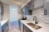 This well-appointed one-bedroom, one-bathroom residence at 95 Audubon Rd in Wakefield, MA offers a thoughtfully designed layout with modern finishes throughout. Light wood-style flooring flows seamlessly across the entire space, creating a cohesive and contemporary feel.

The standout feature of this home is the beautifully renovated galley kitchen, which showcases sleek slate-grey cabinetry with bold black-and-gold hardware, white quartz countertops, a deep stainless steel undermount sink with an oil-rubbed bronze faucet, and a striking elongated hexagon tile backsplash. Full-size stainless steel appliances, including a range, dishwasher, and refrigerator, complete this modern culinary space.

The spacious living room is bathed in natural light from a large picture window with wide exterior views of the surrounding Wakefield landscape, complemented by recessed lighting overhead. The generously sized bedroom offers its own dedicated walk-in closet, providing excellent storage. The bathroom features a clean, bright design with a white vanity, quartz countertop, brushed nickel fixtures, and a tub-shower combination. This residence combines modern style with practical functionality in a well-located Wakefield community.