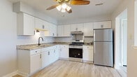 Located at 2128–2198 N Main St in Crown Point, Indiana, this single-floor unit offers a clean, modern interior with a thoughtful layout. The kitchen is a standout feature, equipped with crisp white shaker-style cabinetry, granite countertops, a stainless steel gas range, refrigerator, and an under-cabinet range hood. Light wood-look flooring runs throughout the kitchen and dining area, complemented by a ceiling fan overhead that adds both function and character.

The living area is generously sized, finished with plush neutral carpet and soft gray walls that create a bright, welcoming atmosphere. A sliding glass door opens to an outdoor balcony with iron railing, allowing natural light to fill the space and offering views of the surrounding greenery. An additional window further enhances the airy feel of the room.

The bedrooms are well-proportioned, each featuring carpet flooring, ceiling fans, and windows that bring in natural light. Closet access is provided in at least one of the bedrooms. The bathroom is cleanly appointed with a tub-shower combination, granite-topped vanity with white cabinetry, and wood-look flooring that ties in with the rest of the unit's design. Overall, the space presents a cohesive, updated aesthetic throughout.
