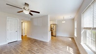 Located at 4573 Wicklow Pl in Virginia Beach, Virginia, this single-floor home offers a thoughtfully updated interior with a clean, neutral aesthetic throughout. The open-concept living and dining area is bathed in natural light from windows fitted with blinds, and features warm wood-look flooring and a ceiling fan that adds both comfort and style. A half-wall partition subtly separates the living space from the kitchen, maintaining an airy, connected feel. The kitchen is well-appointed with crisp white shaker cabinetry extending to the ceiling, granite countertops, a subway tile backsplash, a stainless steel undermount sink, and a full suite of stainless steel appliances including a French door refrigerator with ice and water dispenser, an electric range, and a microwave. A pendant light adds a finishing touch above the kitchen area. The bedroom features plush carpeting, a ceiling fan, and a window that brings in natural light, along with a reach-in closet offering dedicated storage. The bathroom is neatly designed with wood-look flooring, white subway tile surrounding the tub-shower combination, a white vanity with granite countertop, and brushed nickel hardware and fixtures throughout. The overall ambiance is bright, clean, and move-in ready.