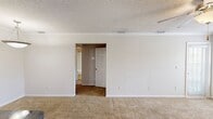 This efficiently designed 590-square-foot, single-floor apartment offers 1 bedroom and 1 bathroom across a thoughtfully laid-out floor plan. The combined kitchen and living room serves as the heart of the unit, where the living area features plush carpeting, crown molding, a textured ceiling with a ceiling fan, and a tile-surround fireplace flanked by two windows that bring in natural light. The kitchen is equipped with light wood cabinetry, dark granite-style countertops, a peninsula with a double sink, track lighting, and stainless steel appliances including a refrigerator with ice maker, a black electric range, and an over-the-range microwave. Tile flooring completes the kitchen space. The 150-square-foot primary bedroom offers carpeted floors, a ceiling fan, and sliding glass doors opening to a private balcony with outdoor views, along with access to a dedicated closet. The full bathroom includes a wood vanity with a granite-style countertop, a large mirror, tile flooring, and a tub/shower combo with white tile surround. Two hallways connect the rooms efficiently, rounding out this compact yet functional living space.