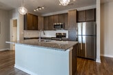 Located at 100 Vintage Alcoa Way in Alcoa, Tennessee, this single-floor residence offers a thoughtfully designed open-concept layout that seamlessly connects the kitchen, dining, and living areas. Rich hardwood-style flooring flows throughout the main living spaces, creating a warm and cohesive aesthetic.

The kitchen is a standout feature, equipped with dark espresso-toned cabinetry extending to the ceiling for ample storage, granite countertops, and a full suite of stainless steel appliances including a refrigerator, range, and built-in microwave. A central island with pendant lighting serves as both a prep area and casual gathering spot, while track lighting overhead ensures excellent task illumination.

The open living area is bathed in natural light and features a ceiling fan for year-round comfort. The bedrooms are carpeted for warmth and comfort, each equipped with ceiling fans and windows that allow natural light to filter in. The two bathrooms are finished with granite-topped vanities, dark wood cabinetry, and tile flooring; one includes a tub/shower combination. A dedicated laundry area with side-by-side washer and dryer units, topped by matching dark wood cabinetry, adds practical convenience. The neutral color palette throughout creates a clean, move-in ready atmosphere.