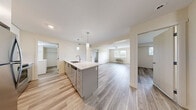 Located at 1465 KLO Road in Kelowna, BC, this well-appointed 2-bedroom, 2-bathroom unit offers a thoughtfully designed single-floor layout. The open-concept kitchen and living area serves as the heart of the home, featuring a large island with a white quartz countertop, modern pendant lighting, grey cabinetry, a grey subway tile backsplash, and stainless steel appliances including a refrigerator, stove, and microwave. Light hardwood-style flooring runs continuously throughout, lending a cohesive and contemporary feel to the entire space. The living area is bright and airy, benefiting from natural light through windows that frame outdoor greenery. Both bedrooms are comfortably sized, each featuring ceiling fixtures and windows that allow in natural light, with the primary bedroom offering generous proportions. The two bathrooms are finished in a clean, modern style with grey cabinetry, white quartz countertops, tile backsplashes, and tub-shower combinations. A dedicated laundry room houses a full-sized washer and dryer alongside additional shelving for storage. A walk-in closet provides further organizational space. Neutral tones and consistent finishes throughout create a calm, move-in-ready atmosphere ideal for comfortable everyday living.