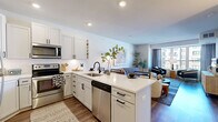This thoughtfully designed one-bedroom, one-bathroom residence in Brooklyn Park, Minnesota offers a modern and comfortable living experience. The open-concept kitchen and living area serves as the heart of the home, featuring white shaker cabinetry, a herringbone tile backsplash, stainless steel appliances, and a large center island with quartz countertops and bar seating — ideal for both cooking and entertaining. Recessed lighting and wood-style flooring run throughout, creating a cohesive and contemporary aesthetic. The living room is bright and inviting, with large windows framing views of the surrounding community and filling the space with abundant natural light. A sliding glass door leads directly to a private balcony, extending the living space outdoors. The bedroom is a peaceful retreat, carpeted for comfort, with generous windows and access to the balcony, offering continued outdoor views and natural light. Two closets provide ample storage throughout the unit. The full bathroom features white cabinetry with black hardware, a tub-shower combination with clean tile surround, and wood-style flooring. A dedicated in-unit laundry area adds everyday convenience, completing this well-rounded and efficiently laid-out residence.