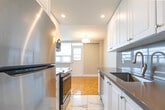 Located at 200 Jameson Ave in Toronto's vibrant Parkdale neighbourhood, this well-appointed 2-bedroom, 1-bathroom unit offers a functional and comfortable layout across a single floor. Warm parquet hardwood flooring flows consistently throughout every room, lending a classic and cohesive character to the entire space.

The kitchen features white shaker-style cabinetry extending to the ceiling for generous storage, stainless steel appliances including a full-size refrigerator and range, and marble-look tile flooring. It opens toward the living area, creating an easy, connected flow.

The living room is bright and spacious, anchored by a wide bank of windows that frame open city views and provide access to a balcony. A baseboard radiator runs beneath the windows, ensuring consistent warmth throughout the seasons.

Both bedrooms are well-sized, each featuring parquet hardwood floors, large windows with natural light, and radiator heating. The primary bedroom includes mirrored sliding closet doors, adding depth and practicality. The second bedroom is equally comfortable with a dedicated window offering additional city views.

The bathroom is finished with clean, large-format white wall tiles and a decorative mosaic accent border, complementing a full soaker bathtub and shower combination. Neutral grey tones throughout the unit create a calm, modern ambiance.