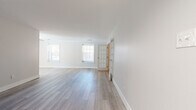 This single-floor space has been thoughtfully updated with a clean, modern aesthetic and a cohesive neutral color palette. The main living area is open and airy, featuring light gray wood-look flooring that extends throughout the common spaces, crisp white walls, and generous natural light provided by multiple windows fitted with blinds. A charming French door with glass pane detailing connects the living area to an adjacent room, adding an elegant architectural touch.

The kitchen is well-appointed with white shaker-style cabinetry, brushed gold hardware, and striking stone-look countertops. Stainless and black stainless appliances, including a range and over-the-range microwave, complete the functional and stylish cooking space.

The bedrooms are carpeted in a warm taupe tone, offering a comfortable contrast to the hard flooring elsewhere. One bedroom features dual sliding-door closets and a window overlooking the exterior, providing ample storage and natural light.

The bathroom is neatly finished with light wood-look tile flooring, a white shaker vanity with a mirrored medicine cabinet, and a tub-shower combination accented by warm travertine-style tile surround. Overall, the space presents a move-in-ready environment with consistent, updated finishes and a welcoming, bright ambiance throughout.