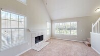Located at 2802 Cheval St in Orlando, FL, this multi-story home spans three floors and offers a well-organized layout across its 2 bedrooms, 3 bathrooms, and a loft. The main living level forms the heart of the home, where an open-plan kitchen and living room create a generous, connected space. The living room is a standout, featuring soaring vaulted ceilings, soft carpeting, and a tile-surround fireplace framed by large windows that flood the room with natural light and offer pleasant outdoor views. The kitchen features a breakfast bar with dark granite-style countertops, white cabinetry, stainless steel appliances, and vaulted ceilings that carry through from the living area. The two bedrooms are carpeted and well-proportioned, with ceiling fans, natural light from windows, and easy closet access. Each bathroom is clean and functional, with white cabinetry, dark countertops, wood-look flooring, and tub-shower combinations with tiled surrounds. A standout feature is the upper-level loft — a bright, carpeted space with a sloped ceiling and ceiling fan, ideal as a flex room or home office. Two staircase connections and a hallway ensure smooth flow throughout all three levels.
