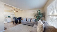 This single-story residence offers a practical and comfortable layout across multiple rooms. The open living and dining area serves as the heart of the home, featuring distinctive painted concrete block walls, a textured ceiling, and wood-look flooring. A ceiling fan overhead provides airflow, while ample seating and a dedicated dining space make the area ideal for both relaxing and entertaining. Natural light filters in through blinds-covered windows, adding brightness to the space.

The kitchen is clean and functional, outfitted with white cabinetry, light countertops, a stylish tile backsplash, and essential appliances including a coil-top range, dishwasher, and refrigerator. Wood-look flooring carries through here as well.

The bedrooms are carpeted for comfort and share the same concrete block wall construction. The primary bedroom includes a ceiling fan and space for a dresser, while a secondary bedroom is thoughtfully arranged as a children's room, complete with a ceiling fan and natural window light. A smaller third room provides an additional sleeping area. The bathroom features a wide vanity with white cabinetry and a framed mirror, alongside a separate tub-shower enclosure.