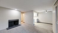 Located at 1007 130th Ave SW in Everett, WA, this one-bedroom, one-bathroom unit offers a practical and comfortable single-floor layout. The combined living, dining, and kitchen area forms the heart of the home, highlighted by a wood-burning fireplace with a dark surround that anchors the carpeted living space. Baseboard heating runs along the walls, ensuring warmth throughout. A sliding glass door fills the living area with natural light and opens to a view of mature trees and lush greenery, providing a tranquil outdoor connection. The kitchen features white cabinetry and light-toned flooring, maintaining a clean and functional aesthetic. A textured ceiling is consistent throughout the unit, adding a classic residential character. The bedroom is a well-proportioned retreat with carpeted floors, a window with outdoor views, a baseboard heater, and a wide sliding-door closet offering ample storage. The hallway connects to three closets in total, providing generous storage throughout. The full bathroom is finished with light wood-look flooring, a single-sink vanity, and a full tub-shower combination. Neutral tones throughout create a cohesive and move-in-ready living environment.