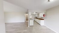 This single-floor, one-bedroom, one-bathroom unit offers a practical and efficient layout with a clean, neutral aesthetic throughout. Light wood-style flooring flows seamlessly across all main living areas, complementing the bright white walls and creating a cohesive, airy feel.

The open-concept living and dining area provides a generous shared space with vaulted ceilings that add a sense of openness beyond the unit's footprint. A half-wall partition separates the kitchen from the living space while maintaining visual connectivity.

The galley-style kitchen is well-equipped with white cabinetry on both sides, dark laminate countertops, a double-basin sink, a white electric range with coil burners, and a full-size refrigerator. Ample upper and lower cabinet storage makes the kitchen highly functional.

The spacious primary bedroom features a window that brings in natural light and includes closet access. The unit benefits from three closets in total, offering exceptional storage capacity. The full bathroom includes a tub-shower combo and an overhead storage cabinet for added convenience.

The overall ambiance is clean and move-in ready, with a simple, utilitarian design that offers a comfortable and well-organized living environment.
