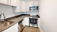 This contemporary apartment, located at 1440 Beacon Street in Brookline, MA, offers a well-designed living space of 660 square feet. The layout comprises two bedrooms, a kitchen, and a closet, all on a single floor. The primary bedroom is notably spacious at 420 square feet, providing ample room for comfortable living.

The apartment features sleek, modern finishes throughout. Light-toned wood-look flooring extends across the living areas and bedrooms, creating a cohesive and airy feel. The walls are painted in a crisp white, further enhancing the sense of space and brightness.

Large windows in the main living area flood the space with natural light, offering views of the surrounding urban landscape. The kitchen, while compact, is efficiently designed with white cabinetry, stainless steel appliances, and dark countertops, creating a striking contrast.

Built-in closets with sliding doors provide convenient storage solutions. The apartment's open plan layout allows for flexible furniture arrangement, making it adaptable to various lifestyle needs. Overall, this apartment combines contemporary design with practical living spaces, ideal for those seeking a modern urban dwelling in Brookline.
