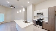 Located in Manor, TX, this well-designed single-story residence offers 2 bedrooms and 2 bathrooms with a clean, modern aesthetic throughout. The open-concept living and kitchen area serves as the heart of the home, highlighted by soaring ceilings, recessed lighting, and a ceiling fan that enhances the airy feel of the space. Light wood-style flooring runs throughout, complementing the neutral color palette of the walls.

The kitchen is a standout feature, equipped with a central island that includes a stainless steel sink and pendant lighting overhead. Dark wood cabinetry contrasts elegantly with white upper cabinets and a white quartz countertop. A full suite of stainless steel appliances — including a refrigerator, electric range, over-the-range microwave — and a white tile backsplash complete the contemporary look.

The bedrooms are comfortably sized, with the primary bedroom offering generous square footage, natural light from a window, and access to a dedicated closet. Both bathrooms feature dark wood vanity cabinets, white countertops, tub-shower combinations with tile surrounds, and well-lit mirrors. Additional closets provide practical storage. The space delivers a cohesive, modern living experience with thoughtful design details throughout.
